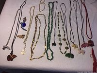 Full view of all necklaces arranged on white cloth showing variety including fetishes, cloisonne pendant, and art glass pendant.
