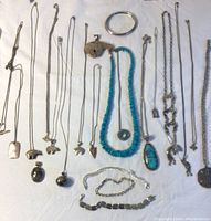 Full overview of laid out Southwestern style silver and turquoise jewelry pieces on white fabric.
