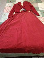 Full view of cranberry red cotton skirt laid flat showing wrinkles and fabric texture.