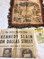 Silk fringed pillow cover with U.S. Army WWII soldier illustrations, American flags, and military scenes laid flat on a surface alongside a folded newspaper and a German map booklet.