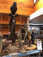 Four bird statues arranged on a metal rack including two eagles, one pheasant, and a bird on a branch.