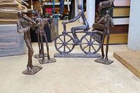 Wide view showing all five cast metal sculptures including four musician figures and one abstract man on bicycle.