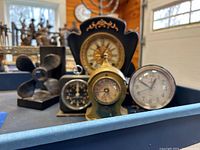 Photo showing three clocks and two bookends (propeller and anchor) arranged on a table.