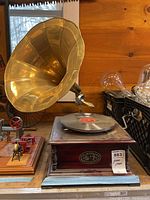 Full view of the gramophone with large brass horn, wooden base, and record on turntable.