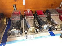 Three musical Rolls Royce decanters arranged side by side on a surface, each in a model car holder with glass decanters and shot glasses present.