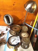 Photo showing group of brass pressure gauges and a metal magnifying lamp with adjustable arm and dome-shaped shade.