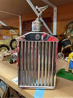 Front view of silver-tone Rolls Royce themed liquor decanter with ribbed grill and sides resembling car headlights.