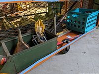 Wooden crates containing wood planes, copper funnel, work light, clamps, and screwdrivers on a cart.