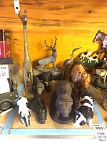 Overview of various animal statues including giraffe, deer, buffalo, pig, cows, hippo, panther/big cat, and a wooden carved buffalo.