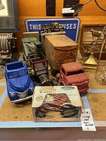 Overview photo showing several vintage toy trucks, a rusty metal truck, Ford book, and a metal Ford sign in the background.