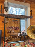 Wide view of the lot showing the carved wooden horse and carriage in front of Thunderflush Water Closet advertising and vintage saw above.