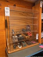 Front view of wood and acrylic display case on shelf with some small objects inside (not included).