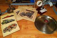 Overview of commemorative plate, unframed prints, framed prints, lamp, hood ornament