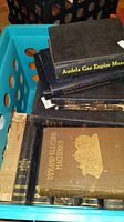 Photo showing a blue crate with multiple vintage books stacked including 'Audels Gas Engine Manual' titles and a book titled 'Dynamo-Electric Machines' with a greenish cover and embossed illustration.