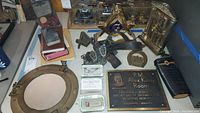 Photo showing porthole mirror, Masonic items, memorial plaque, glass paperweights, belt, and chain