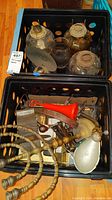 Photo showing four glass oil lamps in a black crate with various vintage office items and a brass menorah including candle holders.