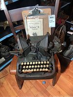 Front view of Oliver No. 9 manual typewriter on a chair with instruction manual displayed behind.