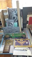 Wide view showing the collection spread on table including pillows, metal plaques, license plates, and model car.