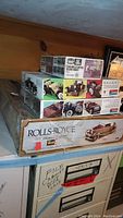 Four Rolls Royce model kits stacked showing box art and labels with wear and storage signs.