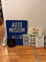 Photo showing all five signs and plaque leaning against a wall, clear view of each item's text and condition.