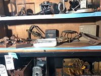 Shelf showing various metal, brass, and vintage collectible items including the stropper devices, lion bookends, and plaques.