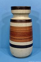 Front view of vintage MCM Scheurich West German pottery vase showing cylindrical form, broad neck, and horizontal brown and orange stripes.