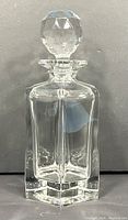 Front view of clear heavy crystal whiskey decanter with faceted stopper, showing hexagonal base and vertical panel sides.