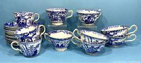 Full view of the 10 Oriental blue and white webbed porcelain cups grouped with matching saucers, showing differences in cup sizes and edge styles on saucers.