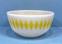 Side view of vintage Fire King milk glass bowl showing yellow diamond pattern on white glass.