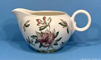 Front angled view of the vintage Johnson Bros Windsor Ware gravy boat decorated with the Azalea floral pattern, showing the round handle and spout.