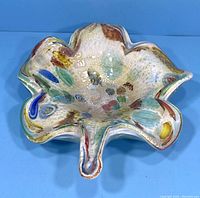 Front view of handblown Murano glass bowl showing organic, petal-like edges and colorful inclusions in glass.