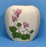 Full view of the white porcelain vase showing the painted cyclamen flowers on front.