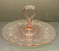 Front and top view of the vintage pink depression glass tray with an attached central handle and etched leaf design.