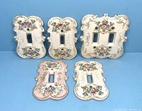 Five vintage floral porcelain switch plates, four white single-switch and one pink double-switch.