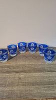 Front view of 6 cobalt blue etched lowball drinking glasses arranged evenly on a wooden surface.