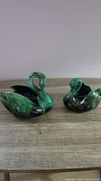 Photo of two ceramic swan planters, one large and one small, showing shape and color details