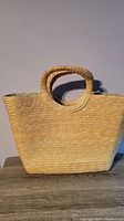 Full view of large straw beach bag with round handles, natural straw color.