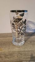 Clear glass vintage vase with silver etched botanical pattern on exterior and silver rim.