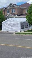 Erected white gazebo tent showing angled front view of white vinyl cover and metal frame