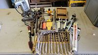 Overview of assorted hand tools including pipe wrench, wire brush, cant hook, caliper, stud puller, plastic stud sensor, and set of auger drill bits.