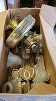 Box of Encon ceiling fan parts including blades, brass fittings, and glass light shades.