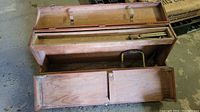 Open wooden toolbox showing compartments and wooden-handled tools inside