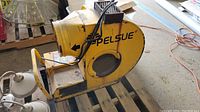 Front and side view of yellow Pelsue 1500S propane heater showing mesh air outlet, metal frame, control box, and handle supports.