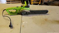 Side view of the green Portland electric chainsaw showing the entire length including power cord