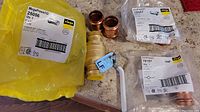 Wide view of entire lot showing 1 Apollo brass valve, 2 copper Propress couplers, 1 MegaPress coupler in package, and other fittings.