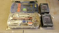 Lot overview showing unopened PBM Bluetooth speaker boxes and plastic tool case on table
