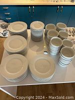 Full set of stacked dinner plates, small plates, and cereal bowls on table showing total quantity