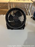Front view of one black small electric fan showing three blades and protective grill