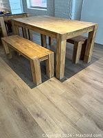 Full view of rectangular solid wood table with benches present