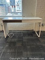 Front view of the white IKEA desk showing one drawer on the right and an empty slot for a missing second drawer on the left; extension cord attached underneath.